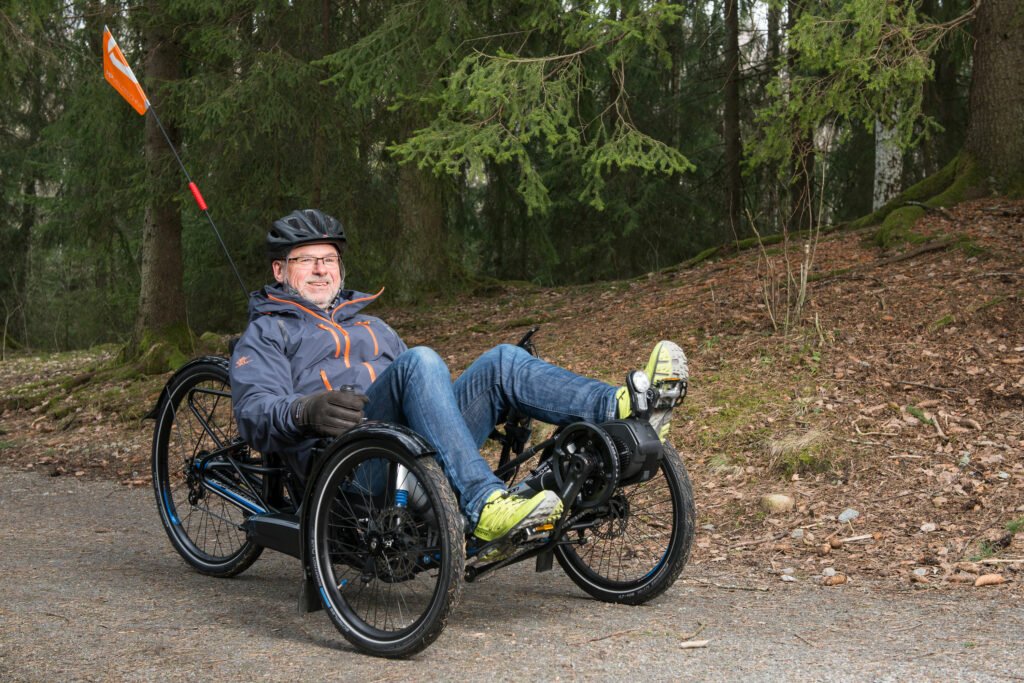 Stål smiler mens han sykler på sittesykkelen Scorpion på grusvei i skogen.