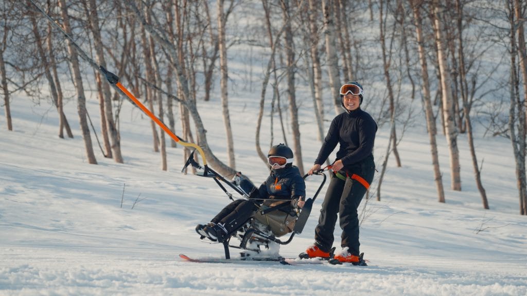 Ledsager og barn tar heis med sitski