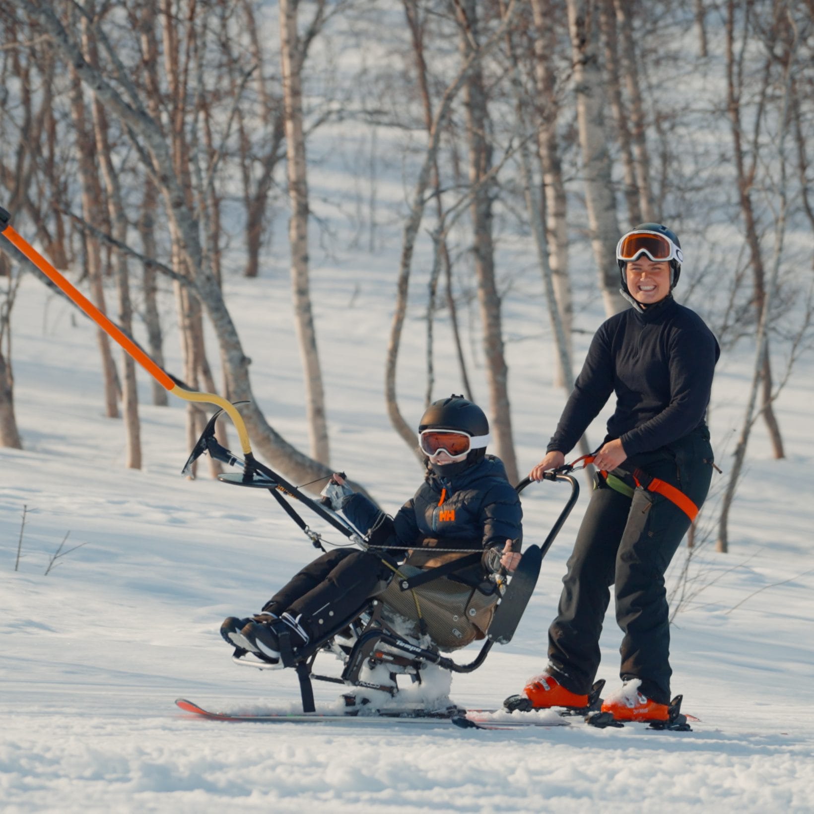 Ledsager og barn tar heis med sitski