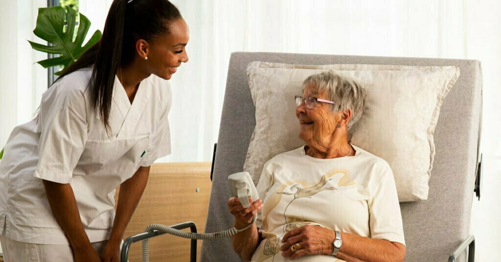 Sykepleier og eldre dame prater sammen