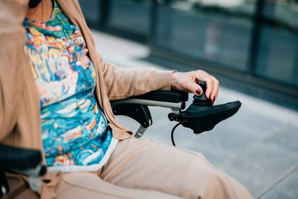 Nærbilde av hånden til Synnøve som holder på joiyticken til en elektrisk rullestol.