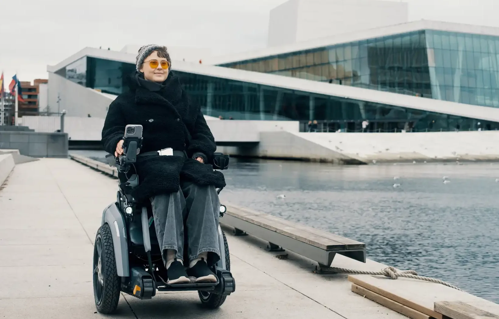 Ung dame i Scewo BRO elektrisk rullestol. Kjørende utenfor operaen