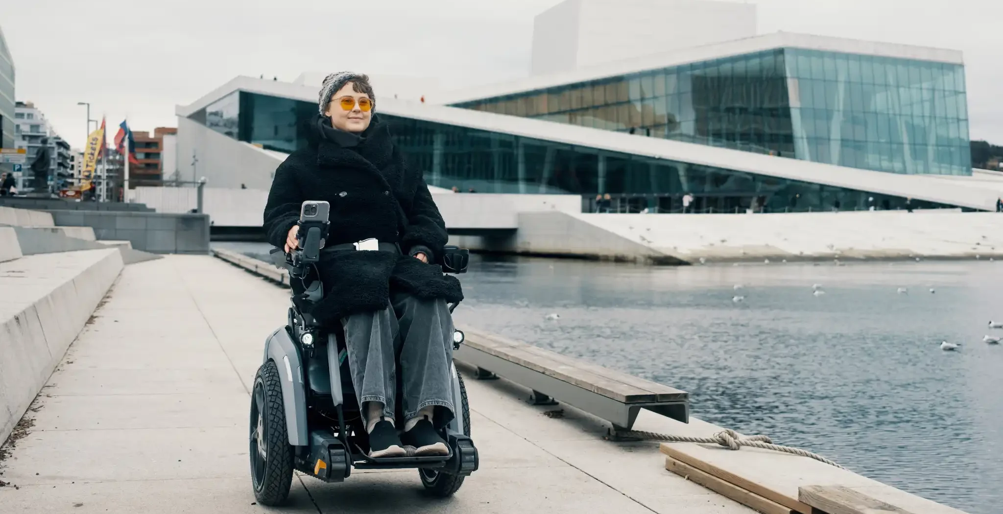 Ung dame i Scewo BRO elektrisk rullestol. Kjørende utenfor operaen