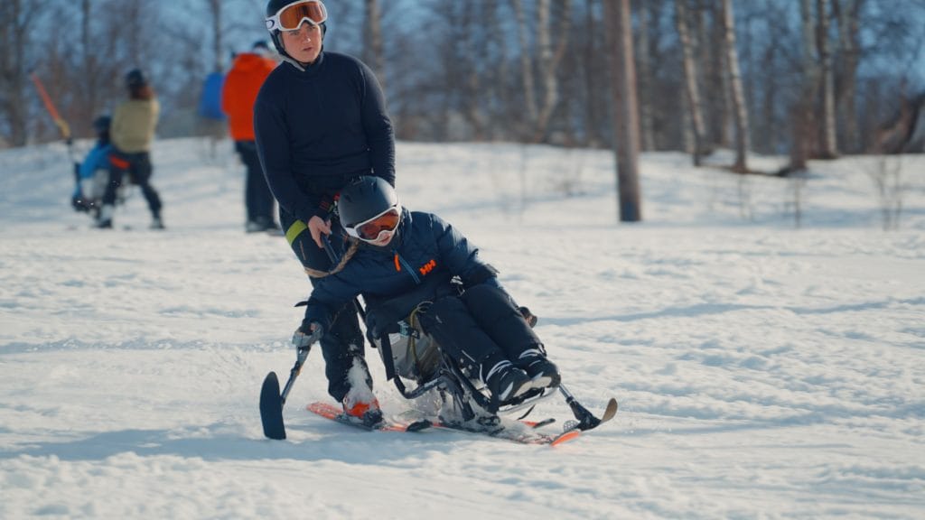 Ledsager og barn som kjører sitski