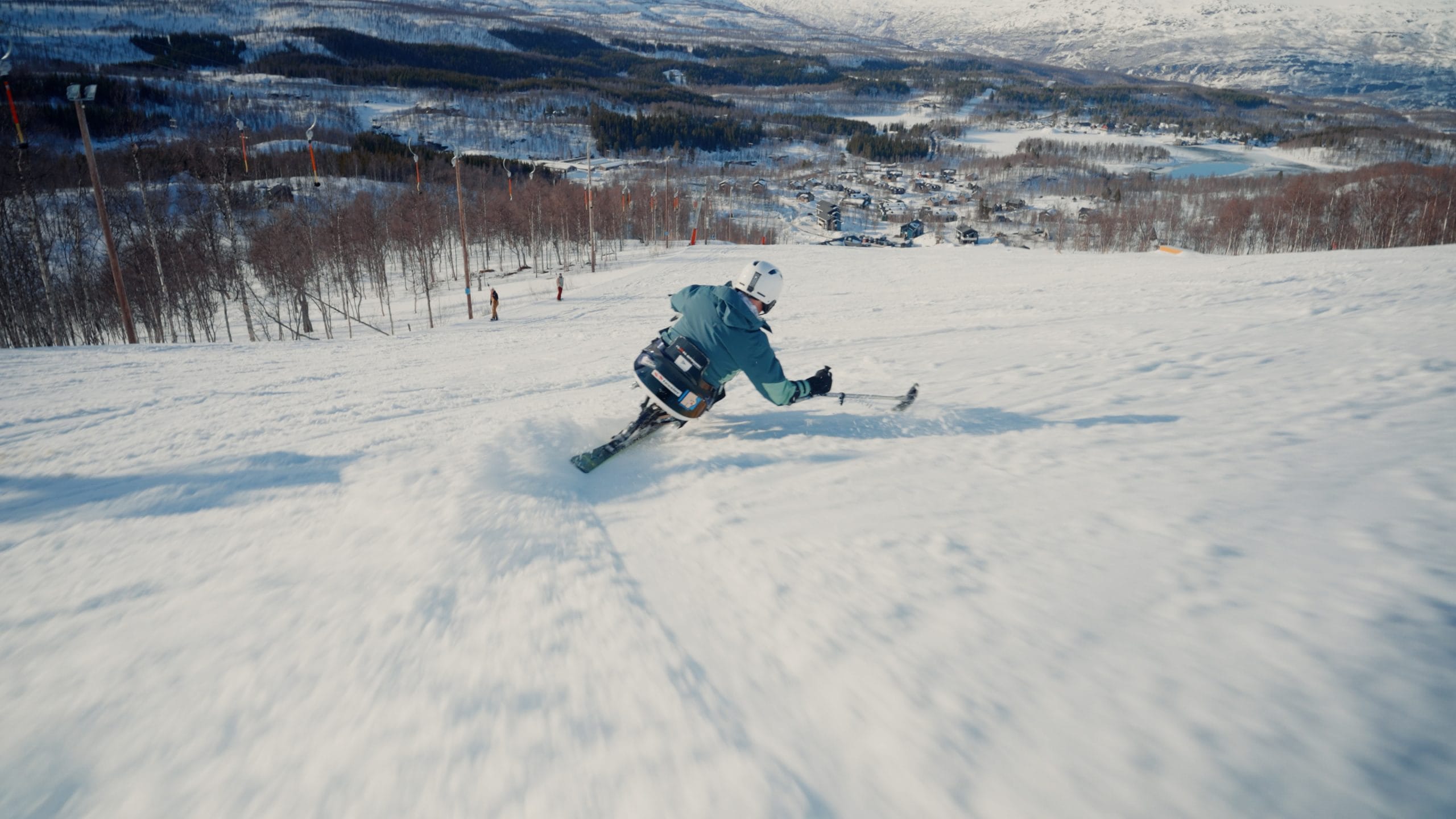 Mann som kjører sitski ned slalombakken