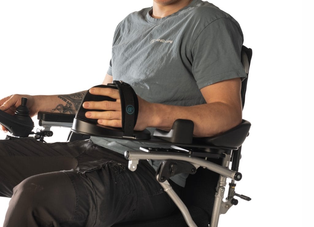 Nærbilde av overkroppen til en mann som sitter i en rullestol. Armen ligger i en Body Point dynamisk armstøtte. Han sitter i en rullestol.