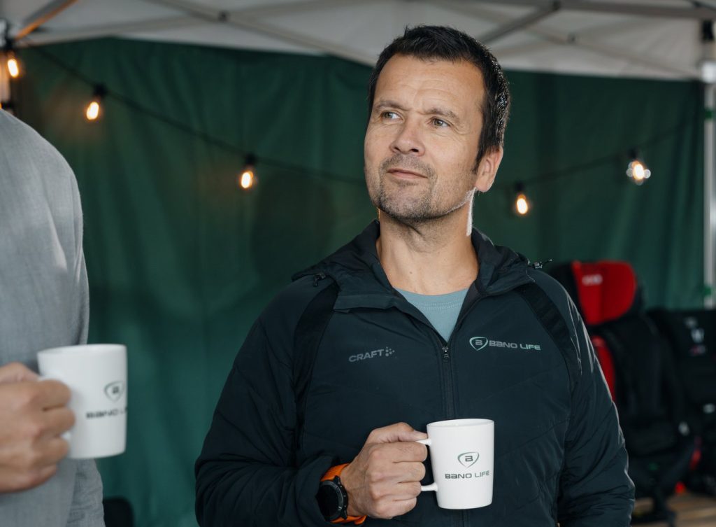 Mann holder Bano Life kaffekopp og prater med kunder på hjelpemiddelmesse