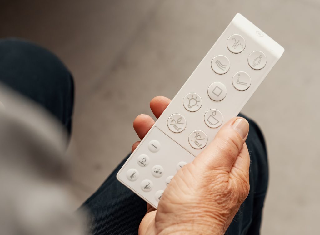 Bruker holder fjernkontroll til Clean Comfort gulvstående toalett med spyl og tørk. 